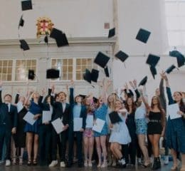 Groep studenten gooit afstudeerhoedjes in de lucht.