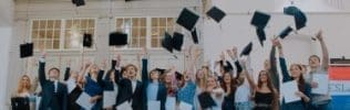Groep studenten gooit afstudeerhoedjes in de lucht.