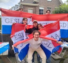 Groep studenten viert geslaagd zijn met vlaggen.