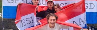 Groep studenten viert geslaagd zijn met vlaggen.
