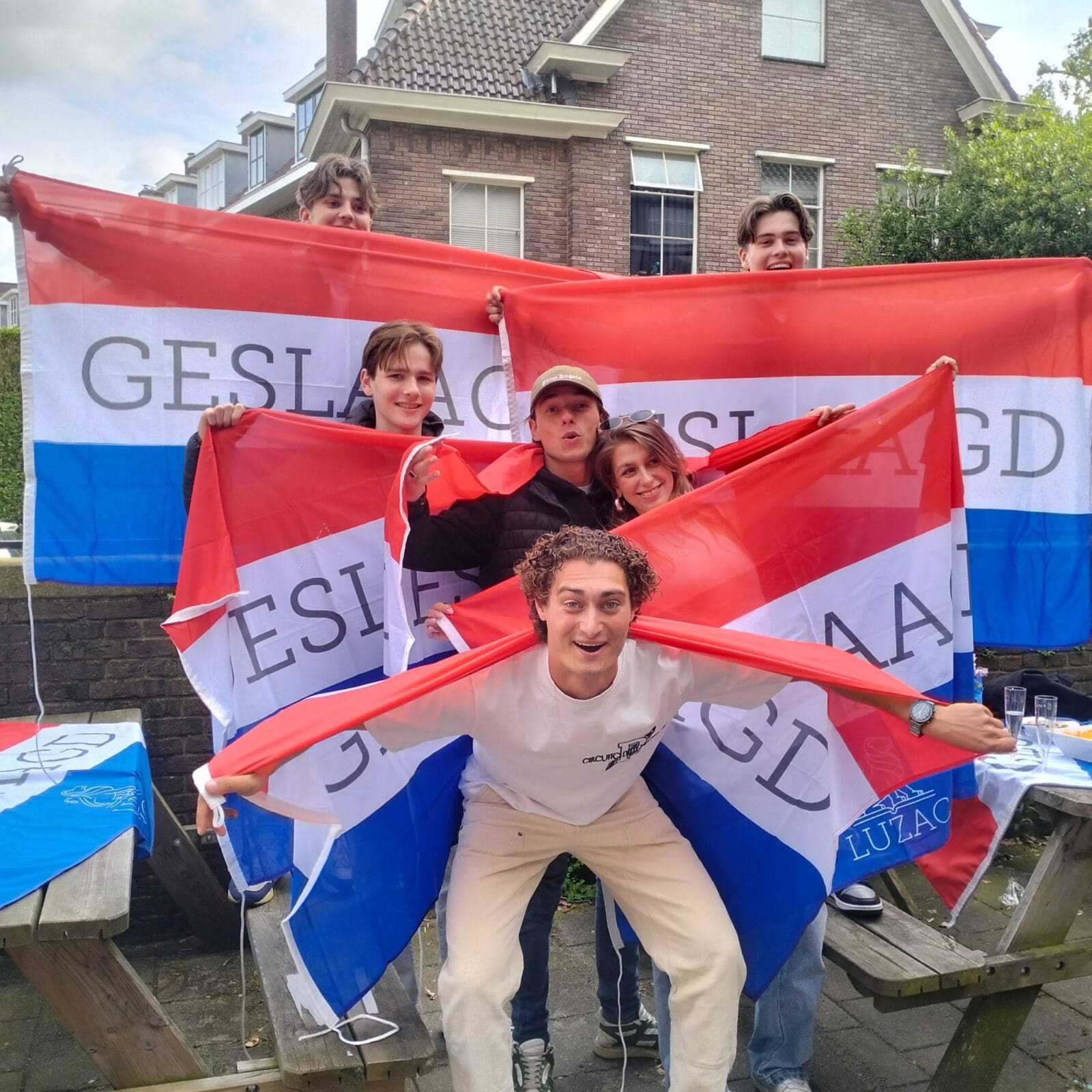 Groep studenten viert geslaagd zijn met vlaggen.