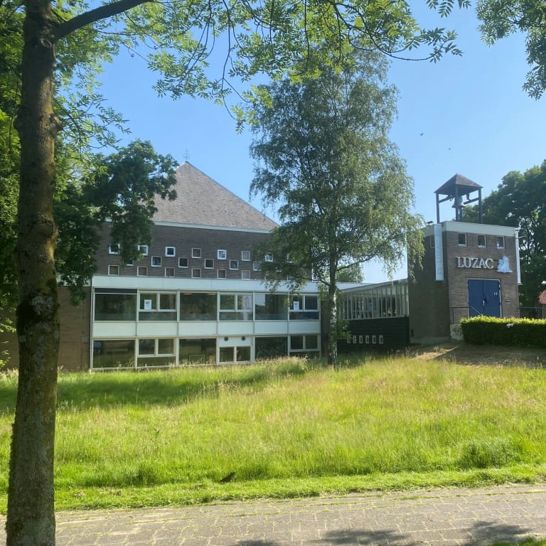 Luzac Breda schoolgebouw met grasveld en bomen.