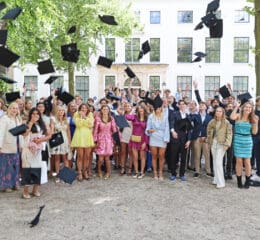 Groep studenten gooit afstudeerhoeden in de lucht.