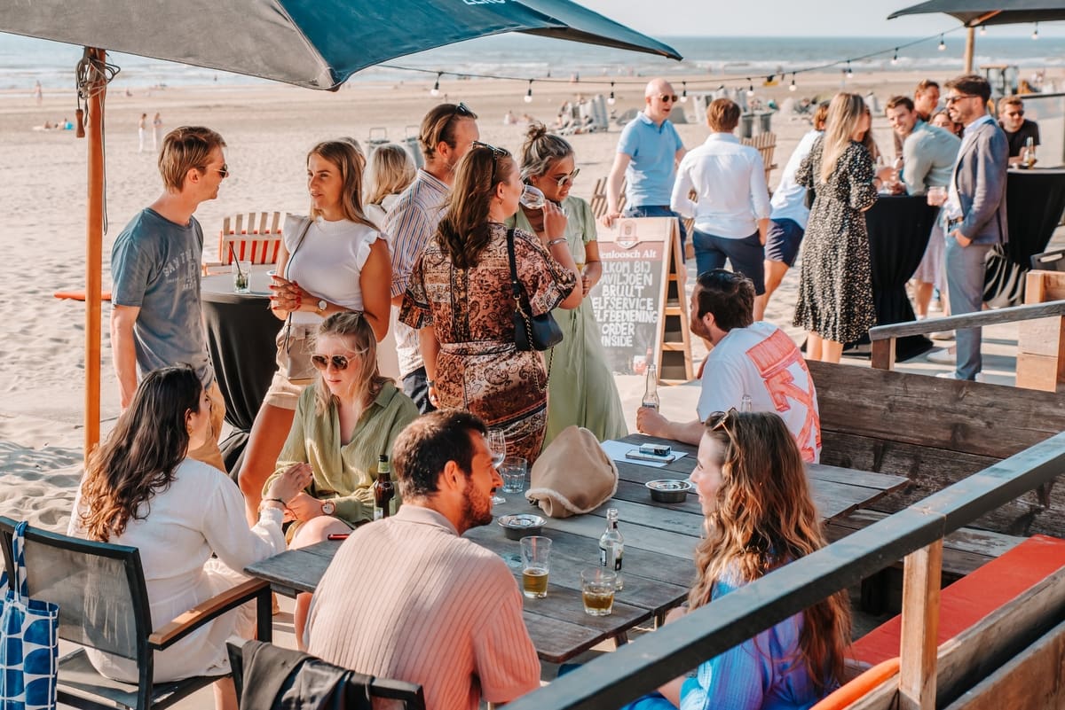 Groep mensen geniet van een zonnige dag op het strand.