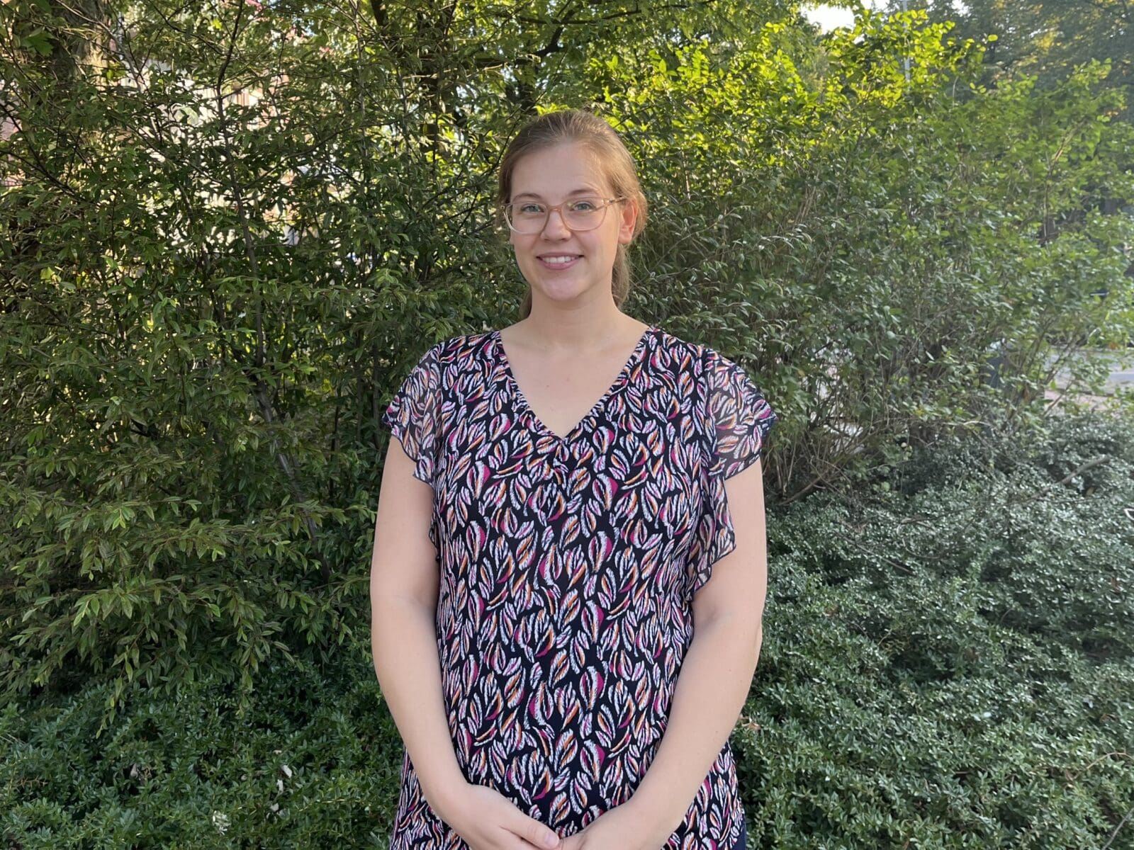 Portret van een vrouw voor groene struiken.