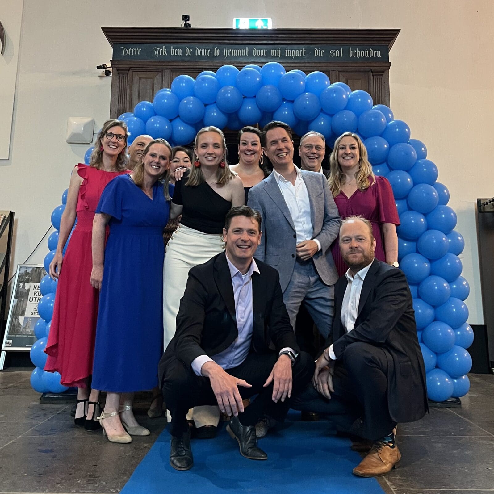Team van Luzac Utrecht voor een blauwe ballonnenboog.