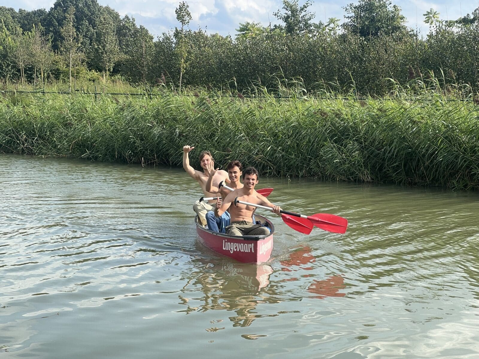 Drie personen in een kano op een rivier.
