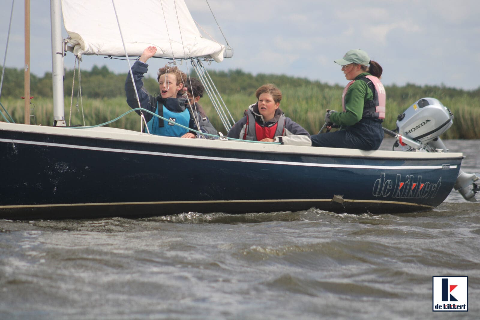 Kinderen zeilen op een meer tijdens een zeilkamp.