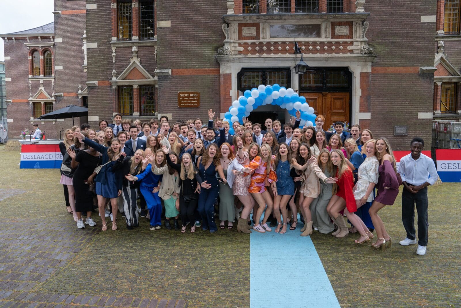 Groep studenten voor Luzac Hilversum gebouw tijdens diploma-uitreiking.
