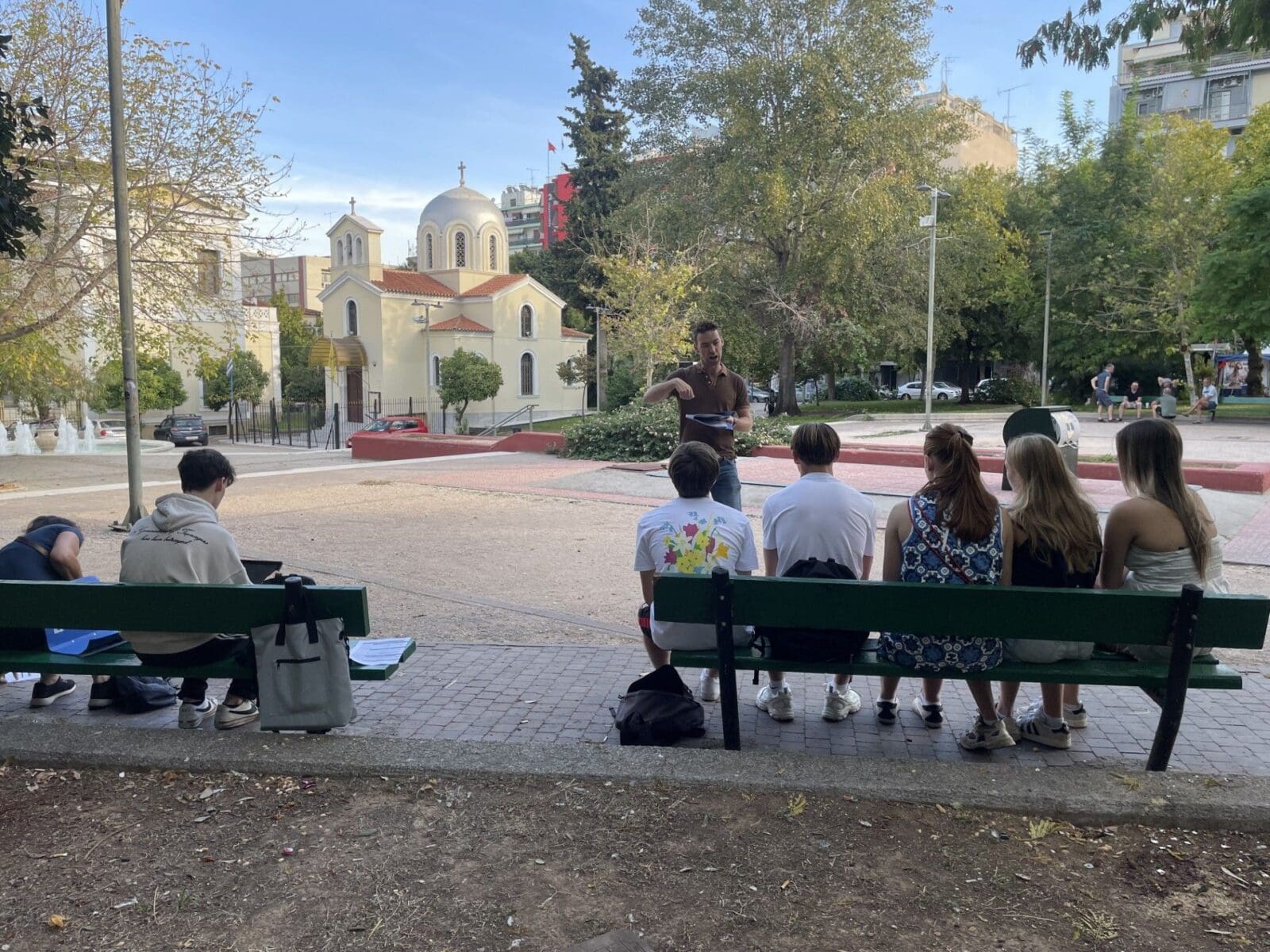 Leerlingen luisteren naar een presentatie in een park in Athene.