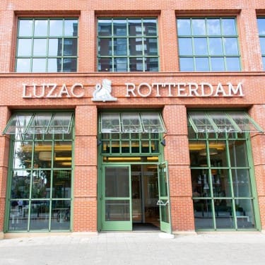 Ingang van Luzac Rotterdam met glazen deuren en ramen.