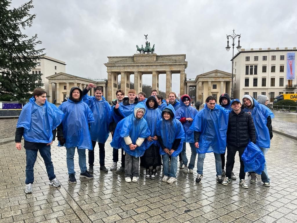 Groep studenten in regenponcho's voor de Brandenburger Tor.