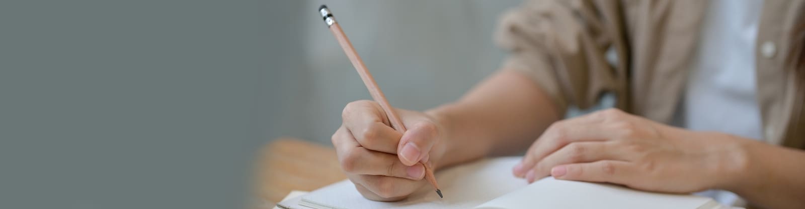 Persoon schrijft met potlood in notitieboekje.