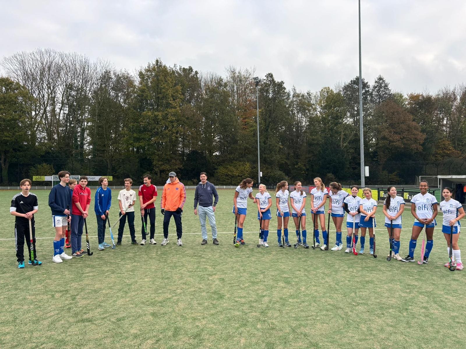 Groep hockeyspelers op een veld tijdens een clinic.