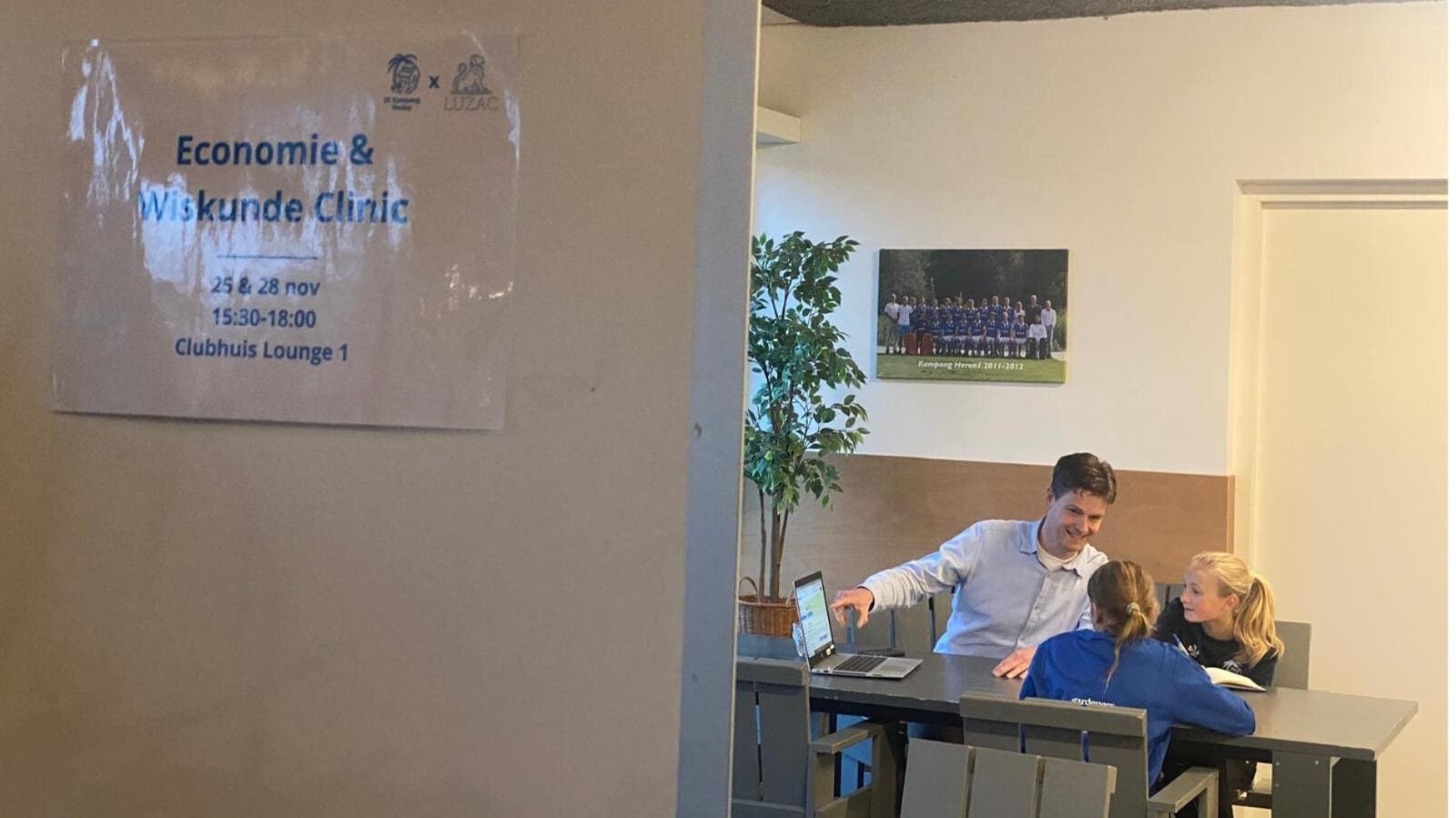 Twee leerlingen in gesprek met een docent tijdens een economie en wiskunde clinic.