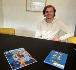 Lachende jongen zittend aan tafel met Kampong magazine en jaarboek